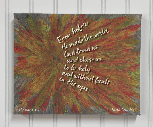 Wrapped canvas of Ephesians 1:4 scripture art with abstract rays in red, green, and gold on shiplap wall