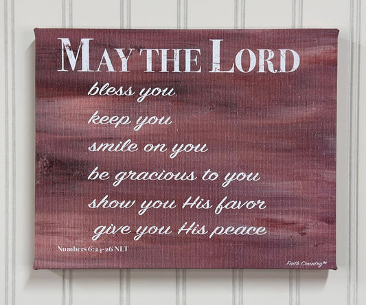 Christian wall art featuring the text 'May the Lord bless you, keep you, smile on you, be gracious to you, show you His favor, give you His peace' in white script on a rustic brown abstract background. Scripture reference from Numbers 6:24-26 (NLT).