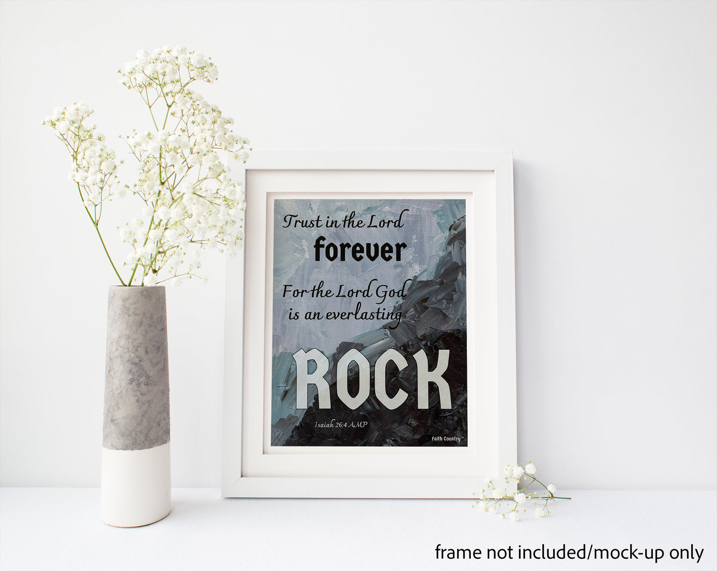 Mockup of scripture wall art with 'Trust in the Lord forever, for the Lord God is an everlasting Rock,' displayed in a white frame next to a vase of white flowers. Minimalist and spiritual decor. Frame not included.